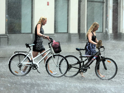 Jaunietes ar velosipēdiem pērkona negaisa laikā.