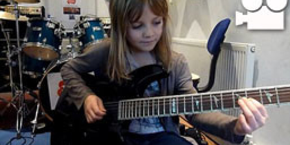 Маленькая девочка играет на гитаре, как рок-музыкант