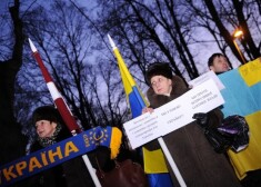 Люди пришли к памятнику с флагами Украины и Латвии и с элементами одежды в цветах украинского флага