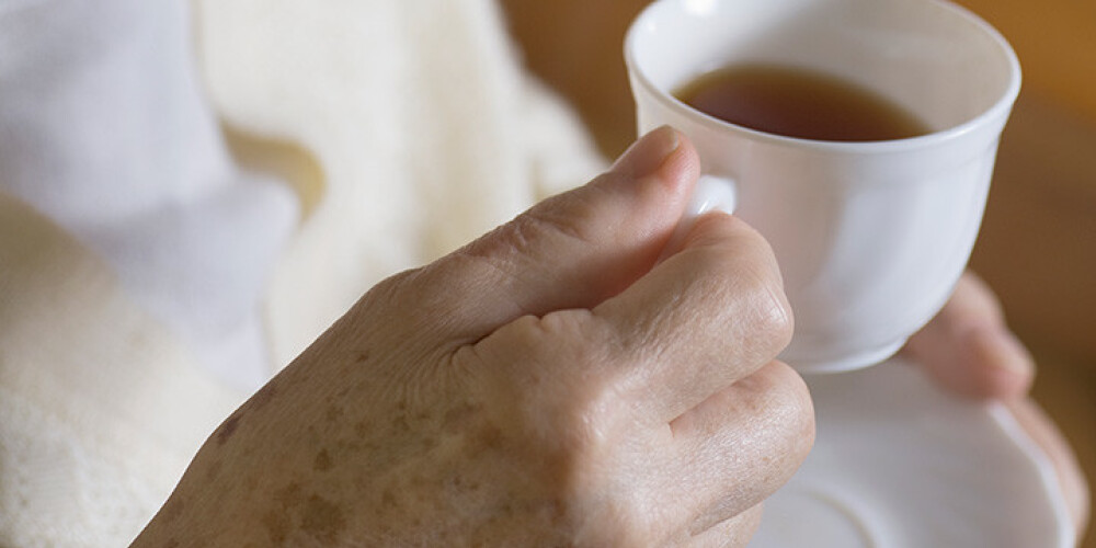 97 gadus veca sieviete ar karstu tēju applaucē muguru