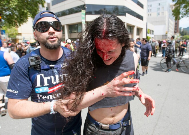 A Trump supporter (L) assists an injured man who was beat up as multiple fights continue to break out between Trump supporters and anti-Trump protesters in Berkeley, California on April 15, 2017. 
Hundreds of people with opposing opinions on President Donald Trump threw stones, lit fires, tossed explosives and tear gas and attacked each other with makeshift weapons as police stood by. / AFP PHOTO / Josh Edelson