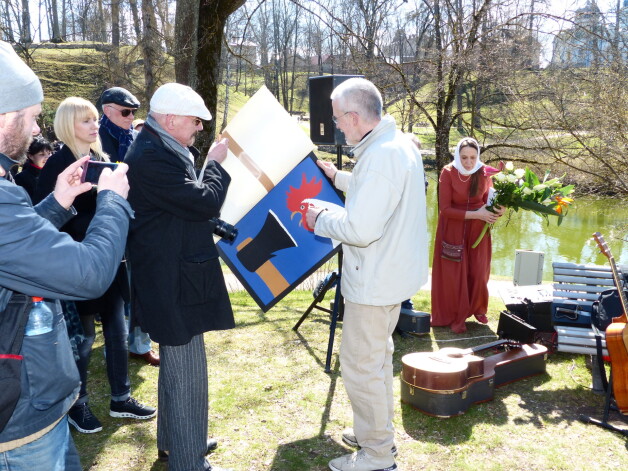 Brāli ar slaveno plakātu par to, kā gailis nesapratās ar cirvi, sveic mākslinieks Juris Dimiters (no kreisās). “Tas esi tu!” skandalozajam brālim teic plakātists. 