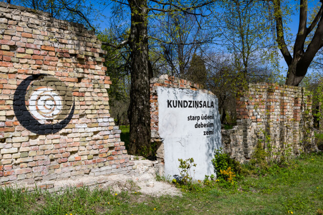 Atbraucējus sveicina uzraksts: "Kundziņsala: starp ūdeni, debesīm un zemi". Lāčplēša dienā vietējie šo sienu noklāj ar svecītēm.