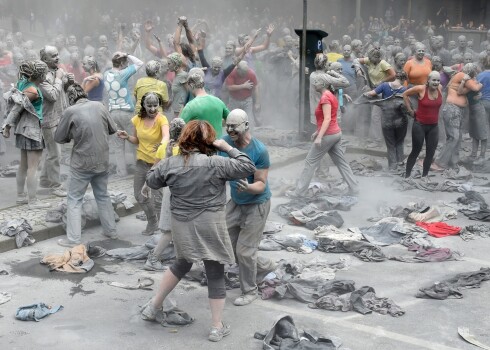 Cilvēki mākslas/protesta akcijas laikā ieziedušies ar mālu. 