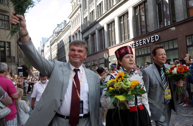 Pasaules koru olimpiādes mākslinieciskais vadītājs Romāns Vanags (no kreisās), nodibinājuma Rīga 2014 vadītāja Diāna Čivle un Vācijas kultūras organizācijas "Interkultur" prezidents Ginters Tīčs (Günter Titsch) 8. Pasaules koru olimpiādes dalībnieku gājiena laikā.