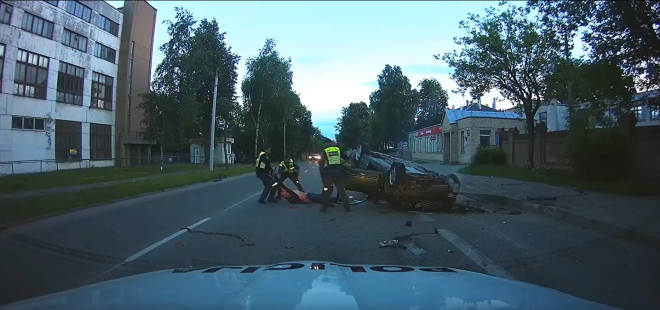 Lietuvas ceļu policisti izvelk avārijā cietušo šoferi no sadauzītās automašīnas.