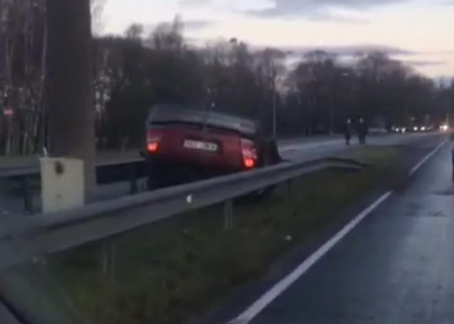 VIDEO: apledojuša ceļa dēļ šorīt Vienības gatvē auto apmeties uz jumta; ir cietušie