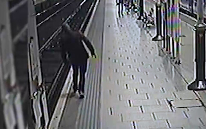 Iereibis pasažieris streipuļo pa platfmormu un cenšas saglabāt līdzsvaru, lai neuzkristu uz sliedēm.