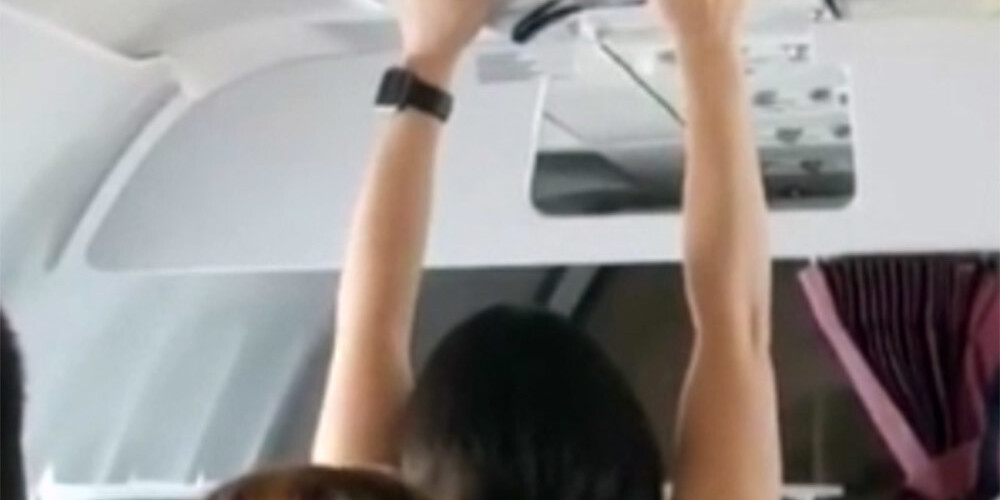 Pasažiere nekautrējas lidmašīnas salonā pie ventilatora žāvēt apakšbikses