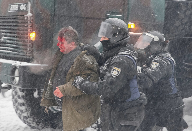 Policisti eskortē aizturētu Saakašvili atbalstītāju.