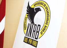 Korupcijas novēršanas un apkarošanas biroja logotips un Latvijas valsts karogs.