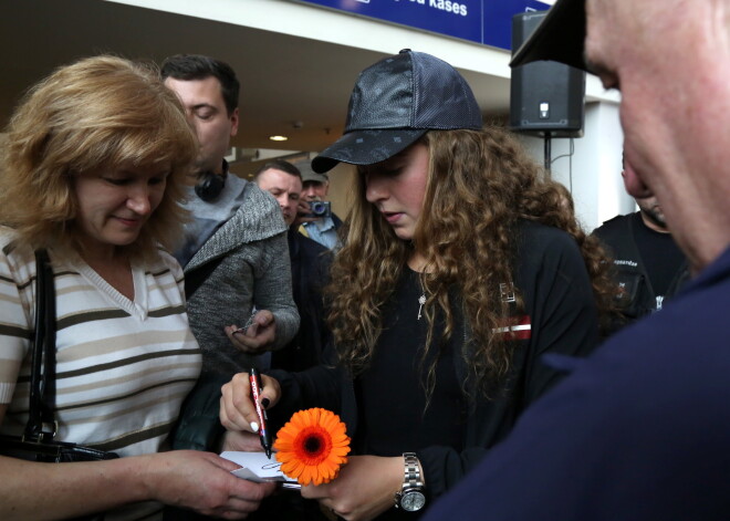 Tenisiste Aļona Ostapenko sniedz autogrāfus tikšanās laikā ar medijiem un līdzjutējiem Rīgas Centrālajā dzelzceļa stacijā pirms došanās uz izslēgšanas spēlēm par iekļūšanu Federāciju kausa ("Fed Cup") 2. pasaules grupā.