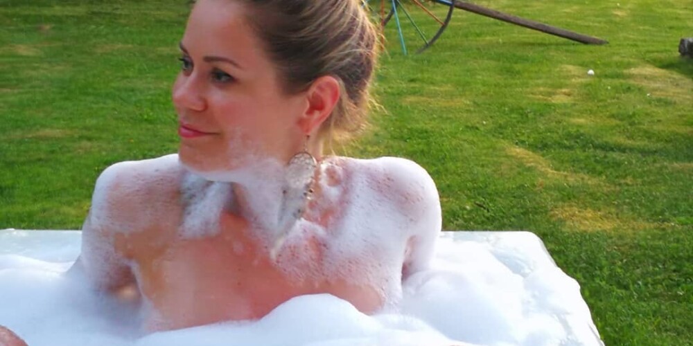 Dziedātāja Jenny May plunčājas vanniņā zem klajas debess
