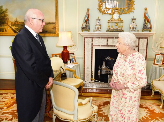 Austrālijas Augstais komisārs Apvienotajā Karalistē Džordžs Brendiss vizītē pie Viņas Majestātes Anglijas karalienes Elizabetes II Bekingemas pilī. Fonā uz viesistabas galdiņa redzama prinča Harija un Meganas fotogrāfija.