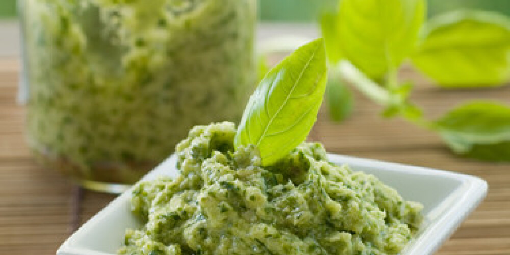 Basil pesto in a small bowl, with fresh basil leaves. Selective focus, shallow doff