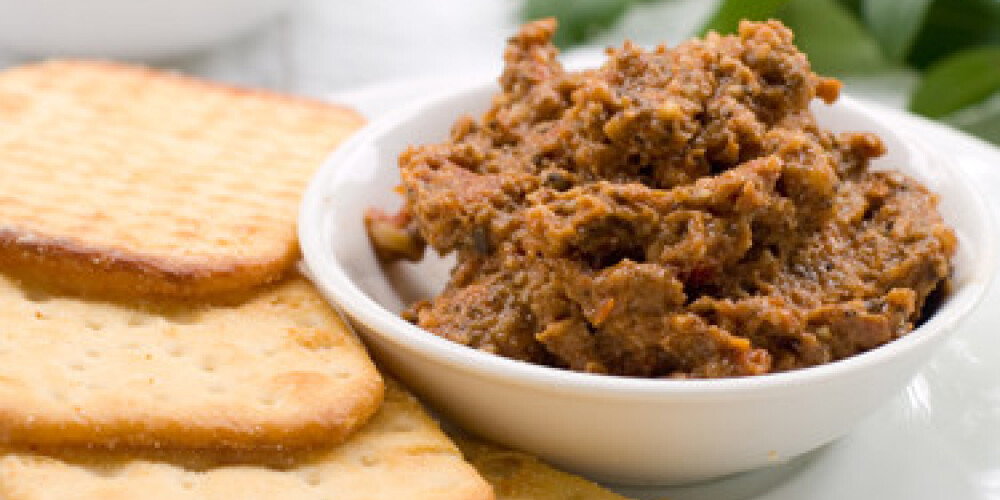 A small bowl of tapenade or olive paste with crackers. Selective focus