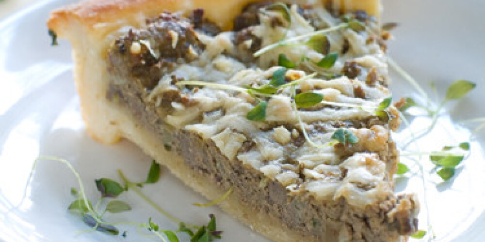 Minced meat pie with cup of chicken stock on background