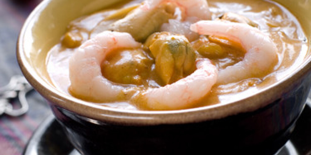 A bowl of seafood curry with shrimp and mussels. Shallow depth of field, selective focus