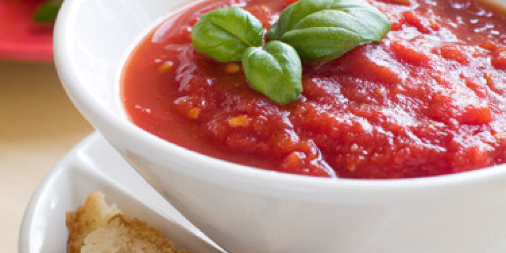 Bowl of tomato soup with bread crouton and basil