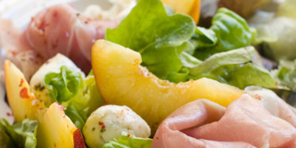 Fresh salad with peach, mozzarella cheese and ham. Selective focus