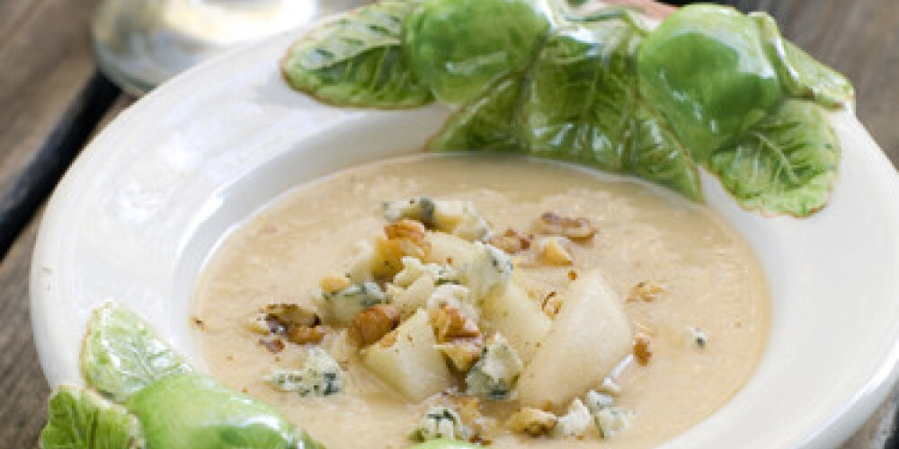 A bowl of soup with pear and blue cheese. Selective focus