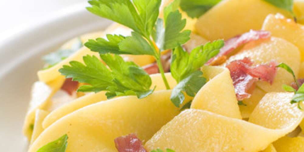 Tagliatelle pasta with prosciutto and parsley, selective focus