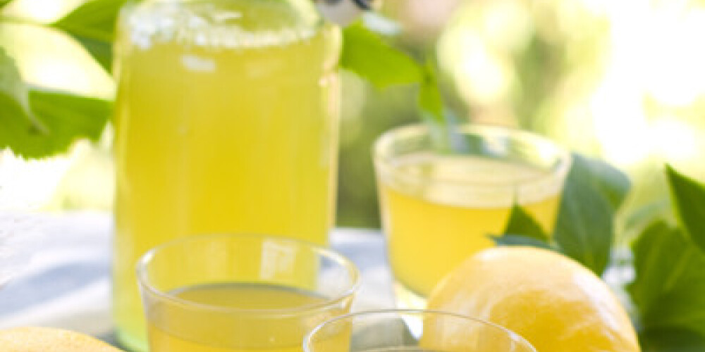 Lemon liqour (limoncello) in glass on natural background. Selective focus