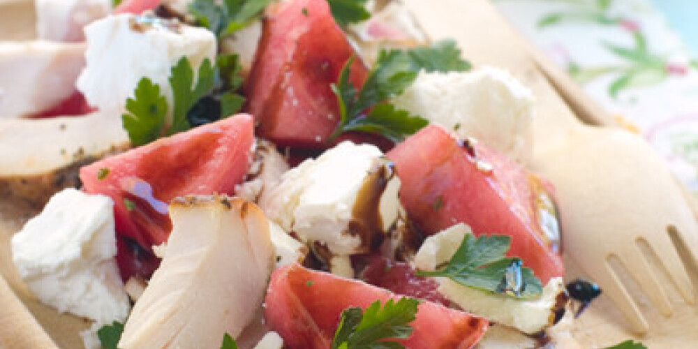 Summer salad from watermelon, chicken and feta on wooden plate, selective focus