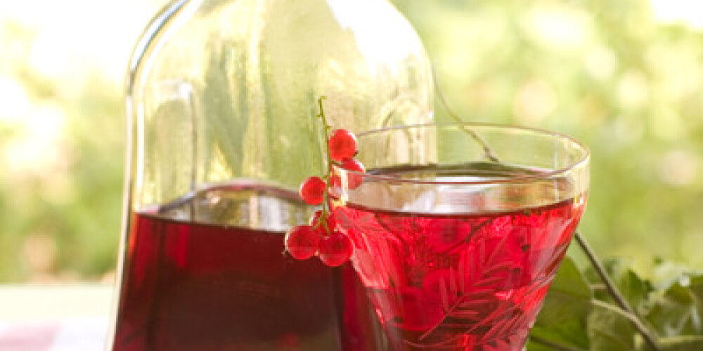 Red currant wine in glass on natural background. Selective focus