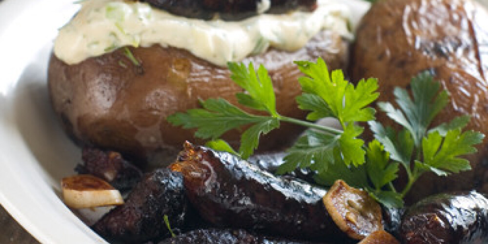 Roasted potato with sauce and blood sausage on plate, selective focus