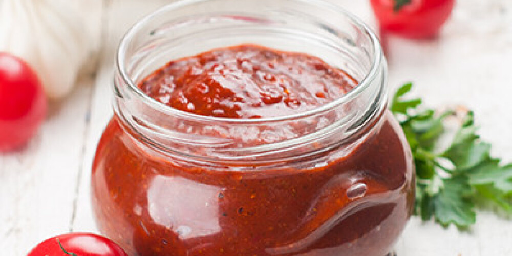 Tomato sauce (jam) with parsley and garlic in glass jar, selective focus