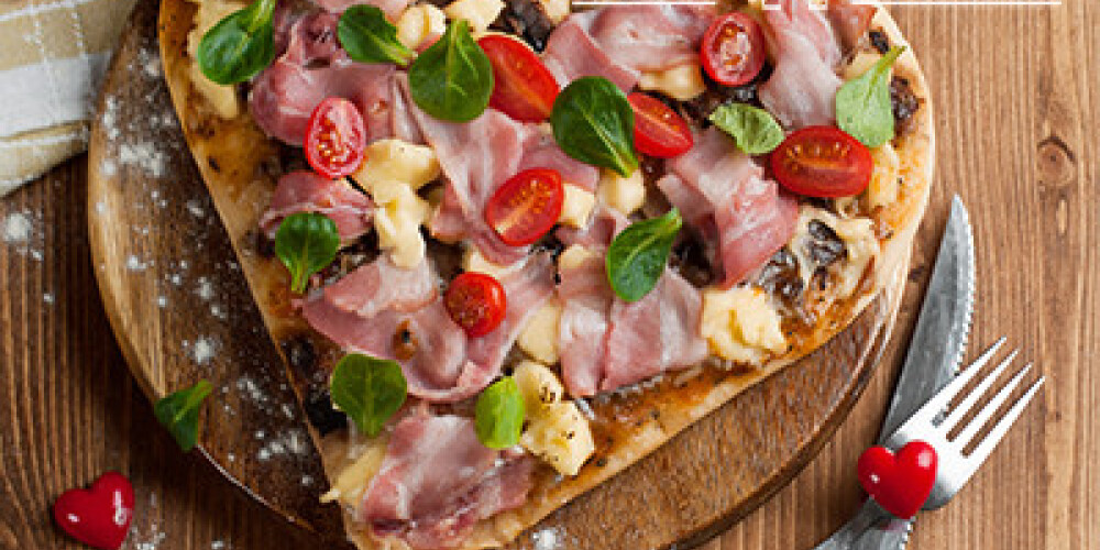 Heart shaped pizza with bacon and vegetables, selective focus