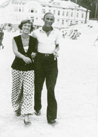 Mākslinieki Kārlis Padegs un Margarita Kovaļevska jeb Čiepa, promenādējot pa jūras krastu. Tā bija vēl viena iecienīta vasarnieku izklaide – pastaigāties, sevi parādīt, uz citiem palūkoties, ar paziņām sasveicināties.