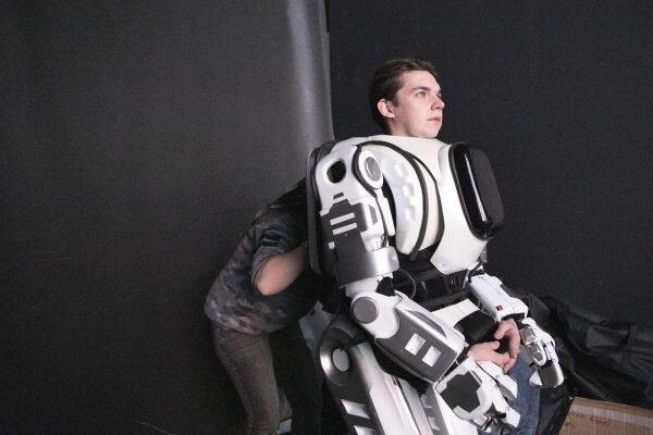 Attēlā redzama foto ar daļēji uzģērbtu robota kostīmu "Aļoša", kuru, spriežot pēc visa, noīrējuši tehnoloģiskā foruma organizatori, pēcāk ietērpjot tajā prasmīgu robota artveidotāju.