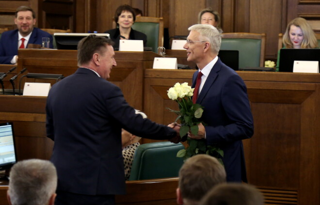 Jaunievēlētais Ministru prezidents Krišjānis Kariņš (no labās) saņem ziedus no bijušā Ministru prezidenta Māra Kučinska pēc balsojuma Saeimas ārkārtas sēdē, kurā deputāti izteica uzticību premjera kandidāta izveidotajam Ministru kabinetam.