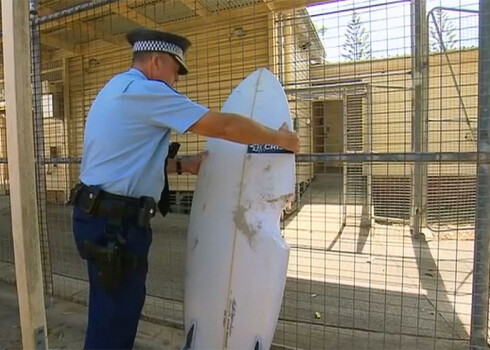 Policisti veic uz dēļa atstātā koduma mērījumu, lai noskaidrotu kāda haizivs sērfotājam uzbrukusi.