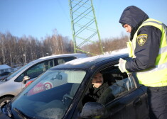 Valsts policijas darbinieks pārbauda autovadītāja dokumentus.