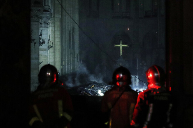 Ugunsdzēsēji aplūko uguns nodarīto postījumu Parīzes Dievmātes katedrāles iekštelpās.