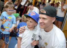 NBA spēlētājs Kristaps Porziņģis dāvā autogrāfu mazajam pacientam viesošanās laikā Bērnu klīniskās universitātes slimnīcā, kur ieradies kopā ar citiem NBA spēlētājiem, lai iepriecinātu mazos pacientus, kuriem vasaras brīvlaikā sanācis nokļūt slimnīcā.