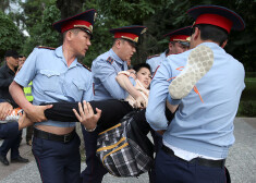 Kazahstānas policisti aiztur protetējošu sievieti.