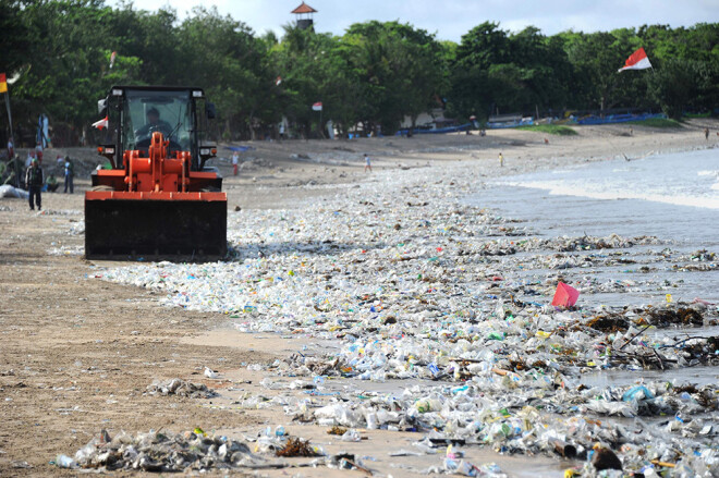 Ekskavators Indonēzijas pludmalē vāc izskalotās plastmasas drazas.