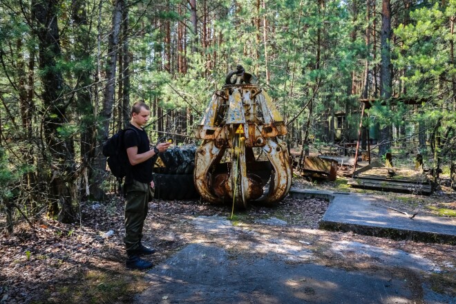 Artūrs Černobiļas atsvešinātības zonā Pripjatā. Fonā redzams kauss, ar ko no uzsprāgušā reaktora jumta ņēma radioaktīvos gružus un meta lejā. Šis kauss ir viena no radioaktīvākajām vietām zonā.