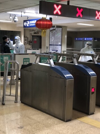 Nedaudzajiem pasažieriem Pekinas metro cilvēki aizsargtērpos mēra temperatūru.