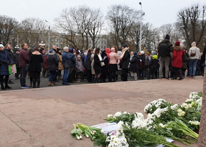 Cilvēku pūlis pie Brīvības pieminekļa ar baltiem ziediem pauž atbalstu Kristīnei Misānei