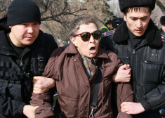 Kazahstānas policijas darbinieku aiztur vienu no protestētājām.