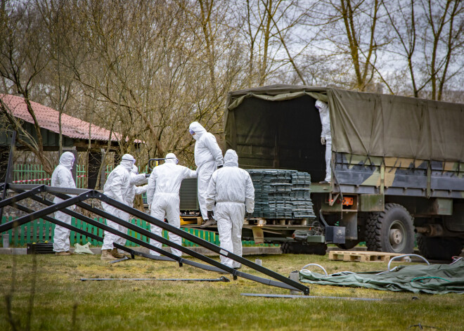 FOTO: Covid-19 uzliesmojuma skartajā patversmē „Zilais Krusts” uzstāda armijas teltis; saslimušo stāvoklis esot labs