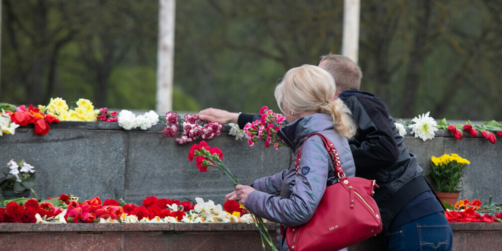Люди приносят цветы к памятнику Победы, соблюдая ограничения на собрания