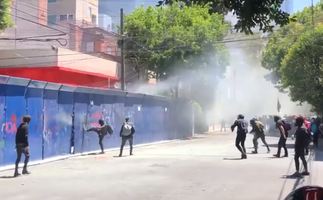 Pie ASV vēstniecības sapulcējās jaunieši kapucēs - anarhistu kustības dalībnieki.