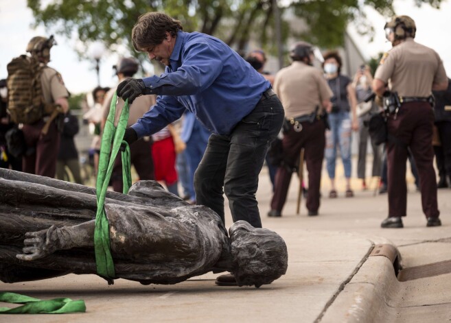 Protestētāji pie nogāztās Kolumba statujas Minesotā.