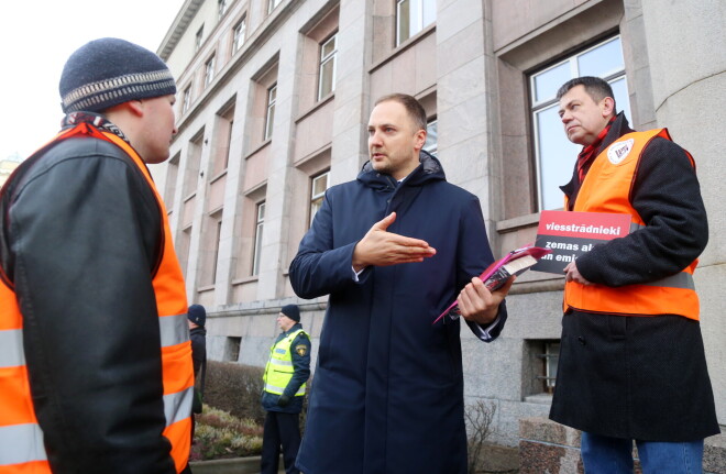 Pērn decembrī pie Ministru kabineta notika nacionālās savienības „Tausnīgums” protests pret iespējamām izmaiņām viesstrādnieku piesaistes regulējumā. Pirms valdības sēdes ar nacionālistiem diskusijās iesaistījās iekšlietu ministrs Sandis Ģirģens (centrā, no labās – partijas saraksta līderis šajās Rīgas domes vēlēšanās Vilnis Strods).